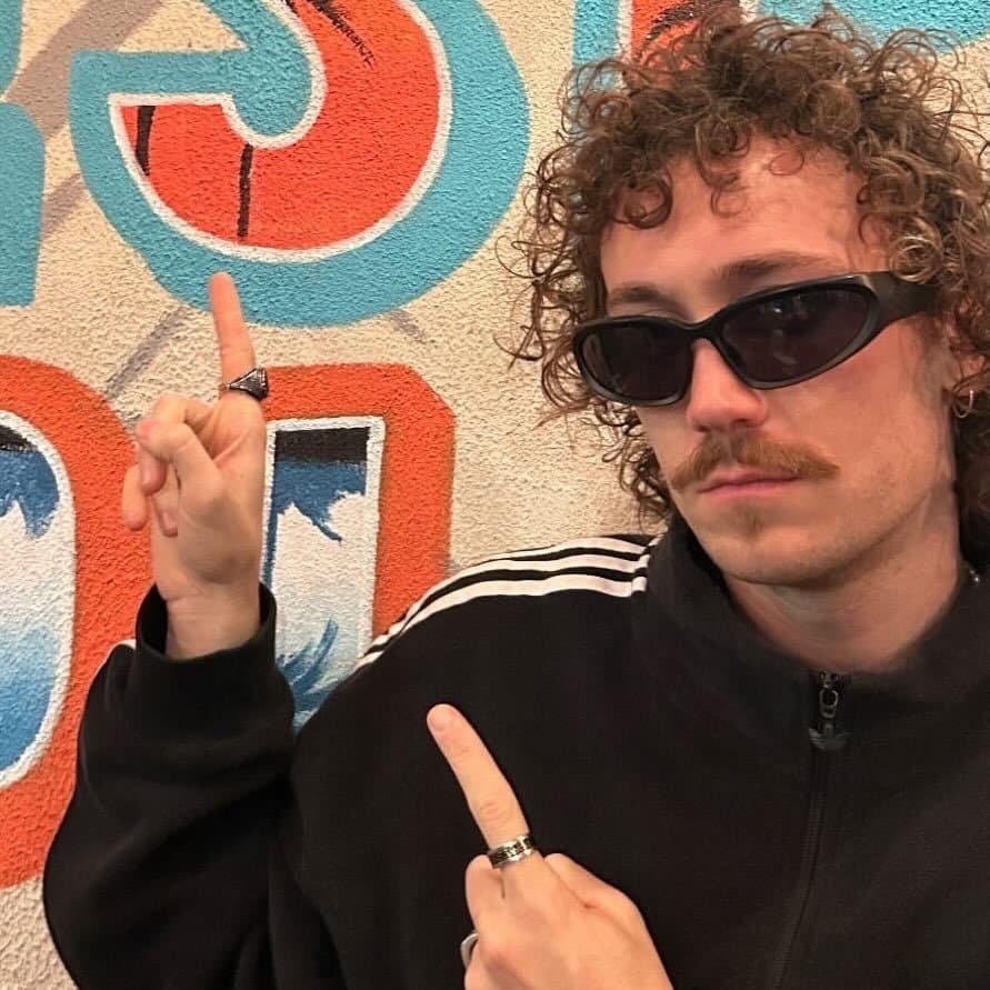 Retrato de Julián Zancada con anteojos de sol frente a un mural de colores